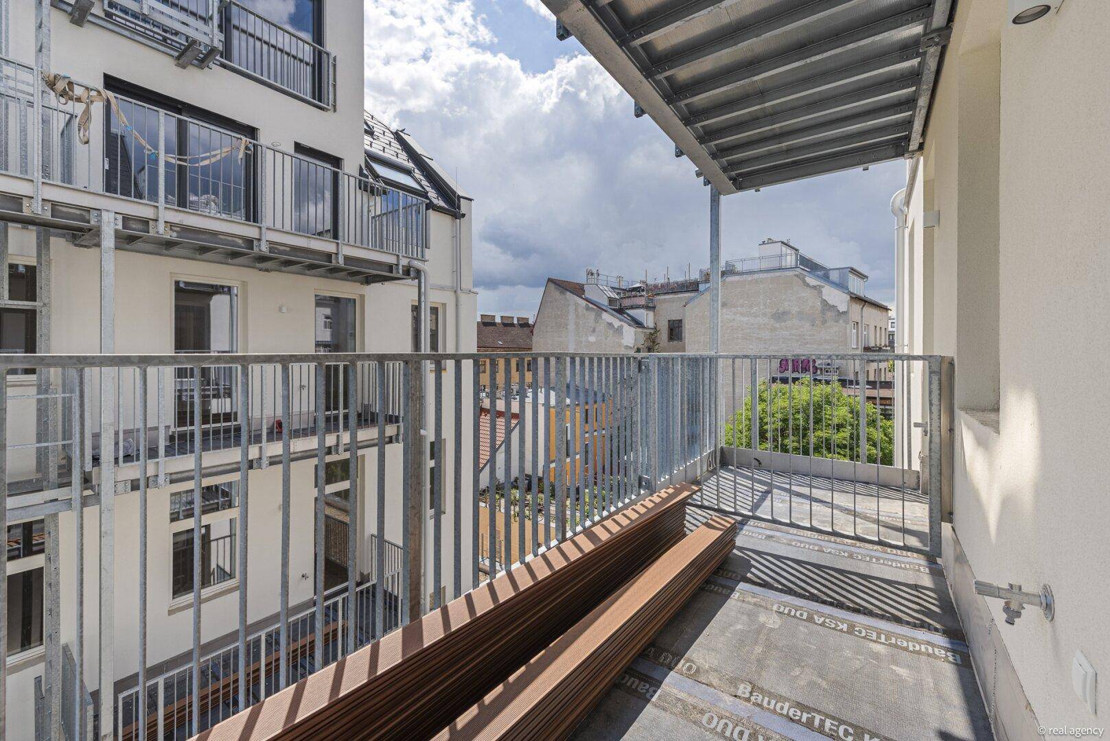 Balkon mit Metallgeländer und Blick auf die umliegenden Gebäude, noch im Bau befindlich.
