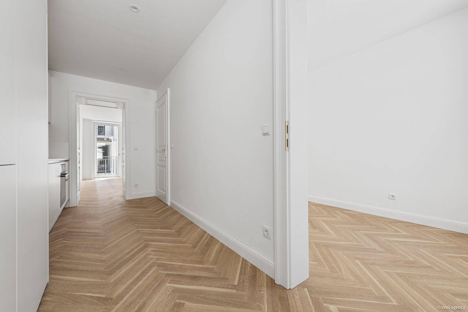 Heller Flur mit Fischgrätparkett, der verschiedene Zimmer der Wohnung miteinander verbindet.