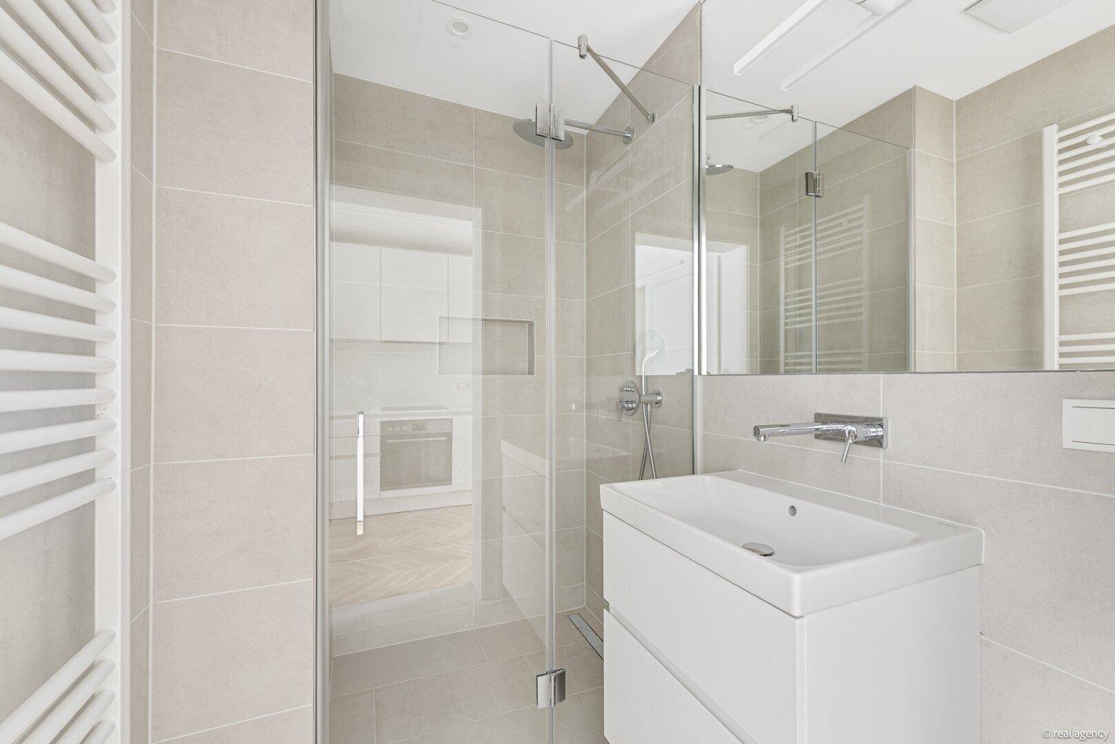 Modernes Badezimmer mit begehbarer Dusche, Waschtisch und beheiztem Handtuchhalter.