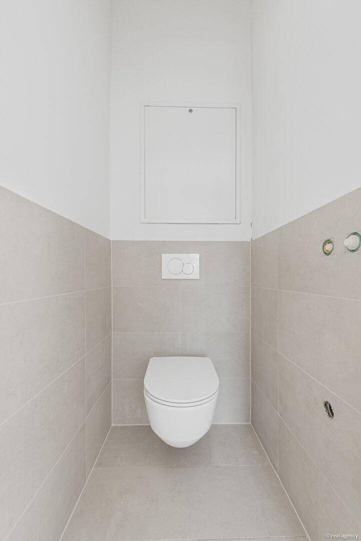 Modernes Gäste-WC mit Wand-WC und hellgrauen Fliesen.