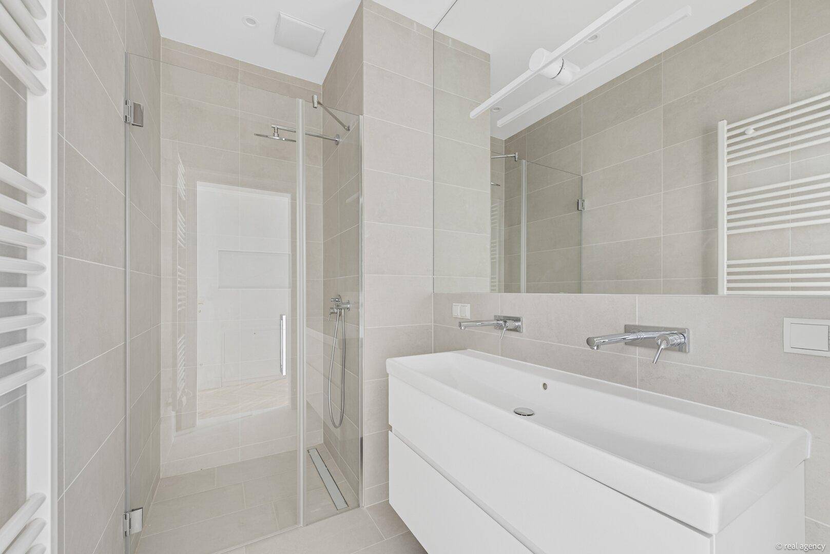 Modernes Badezimmer mit ebenerdiger Dusche, Waschtisch und großem Spiegel.