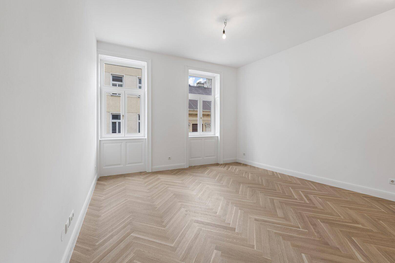 Geräumiges, helles Zimmer mit elegantem Fischgrätparkett und hohen Decken.