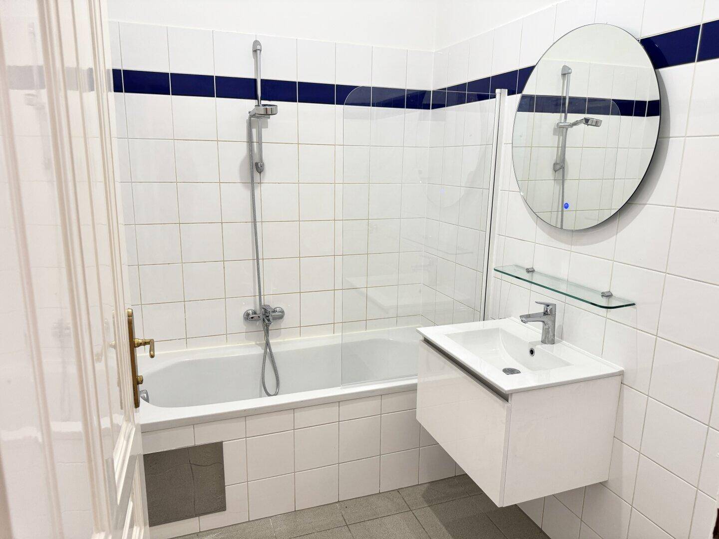 Modernes Badezimmer mit Badewanne, Duschfunktion, Waschbecken und Spiegel, in weiß-blauer Farbgebung.