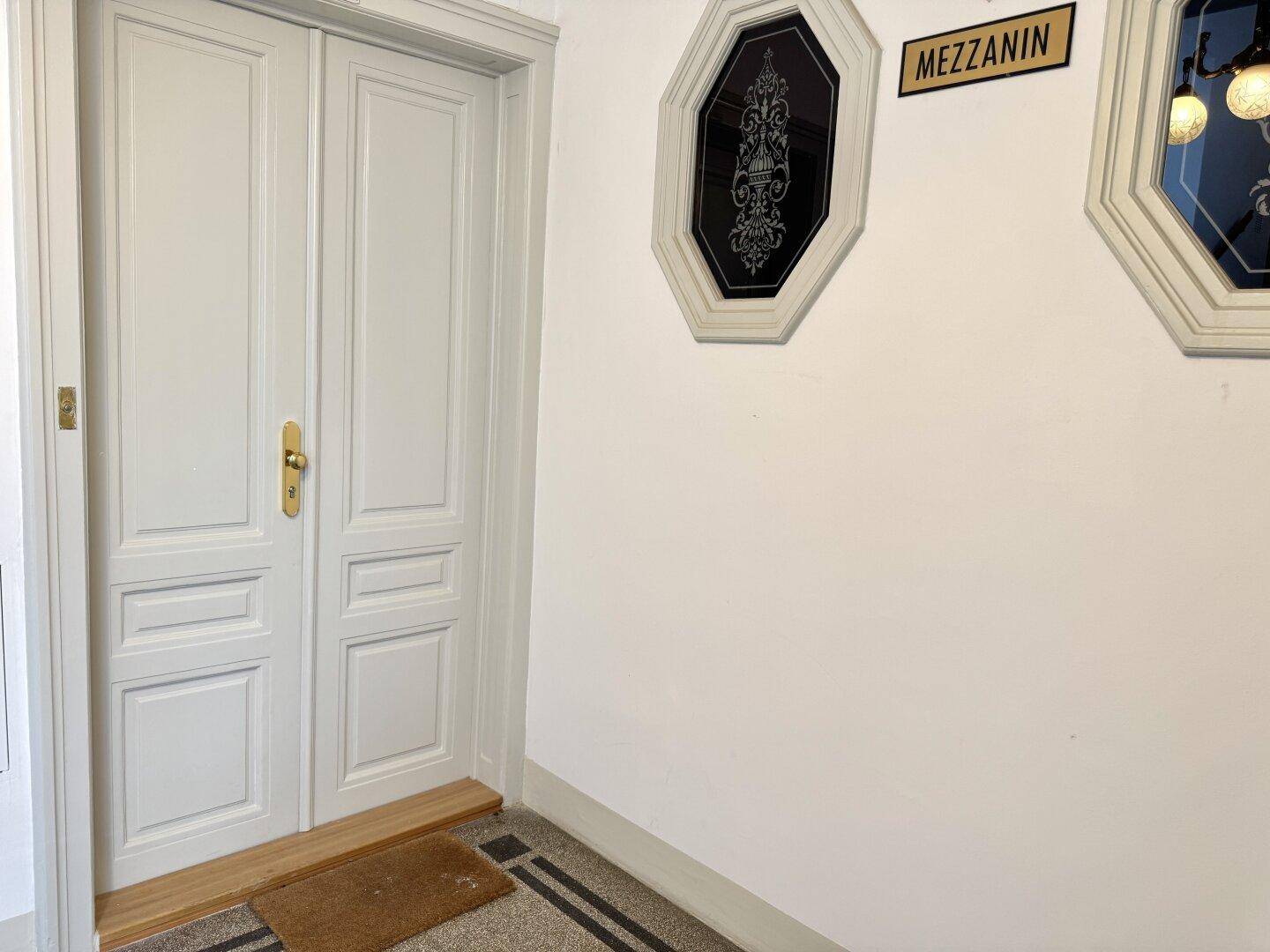 Eingangstür zum Mezzanin mit eleganten Verzierungen und klassischem Design.