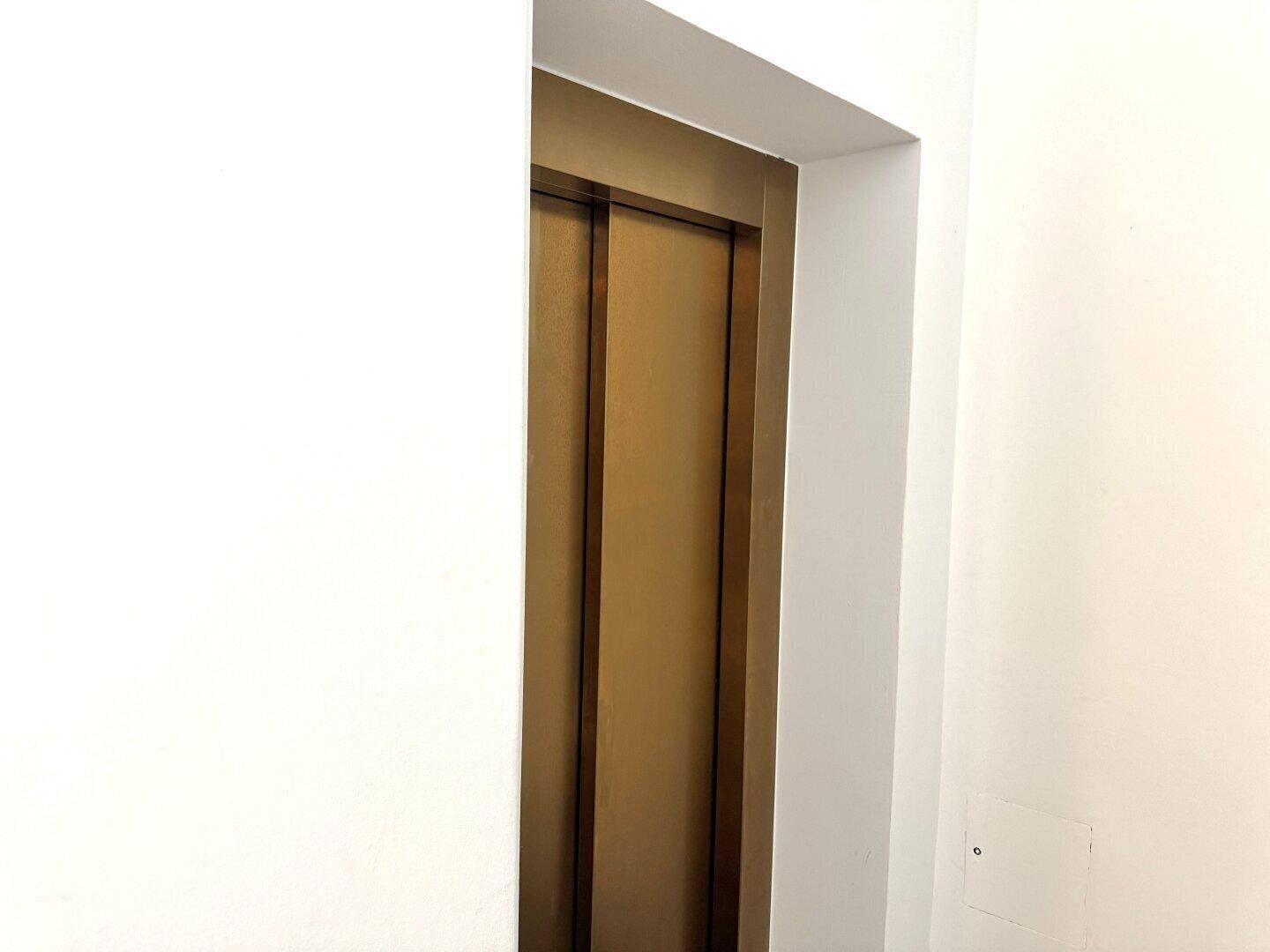 Moderne Aufzugstür in einem hellen Flur, die den Zugang zu den Etagen ermöglicht.
