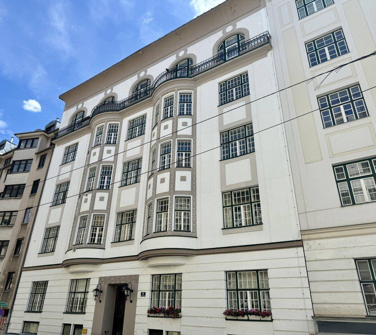 Historische Fassade eines eleganten Stadtgebäudes mit vielen Fenstern und Balkonen.