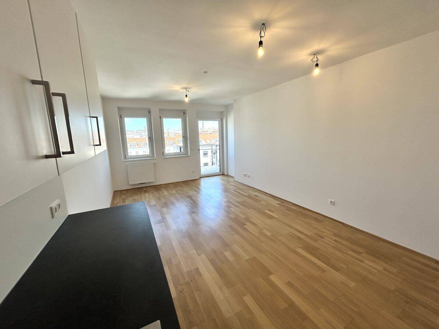 Heller Wohnbereich mit Holzboden und Blick auf die Stadt durch die Fenster.