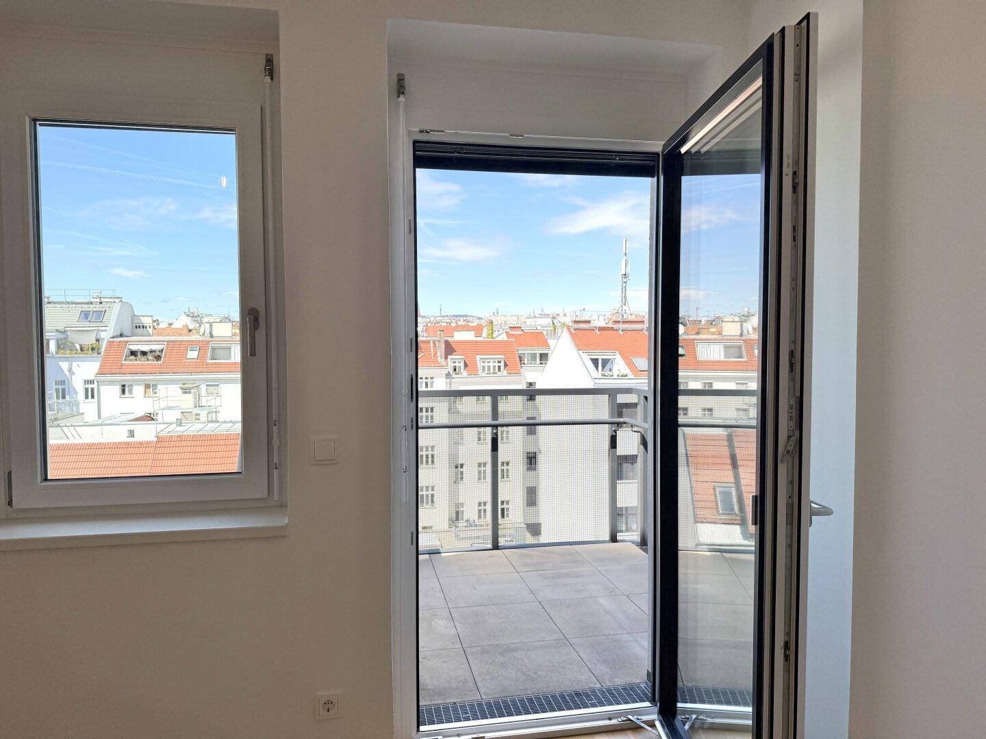 Heller Raum mit Zugang zu einem Balkon, der einen weiten Stadtblick bietet.