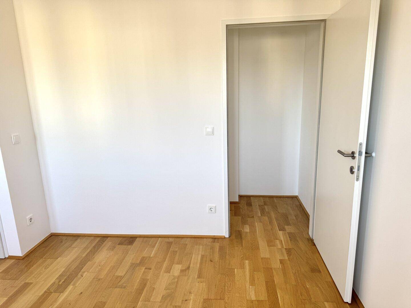 Geräumiges Zimmer mit Holzboden und einem offenen Bereich, ideal als begehbarer Kleiderschrank.