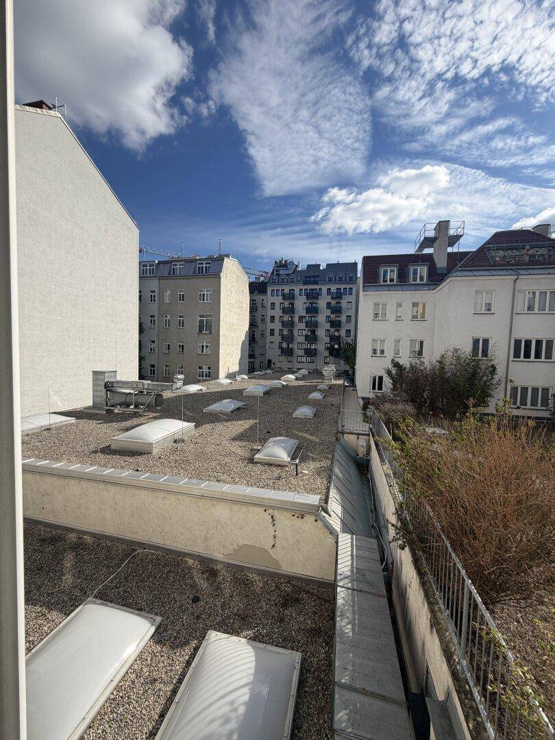 Blick über Dächer mit Dachfenstern und umliegenden Gebäuden.