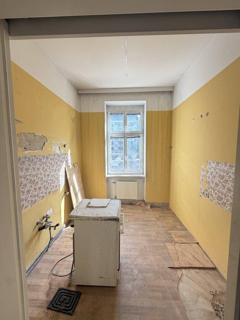Leere Küche in Renovierungszustand mit gelben Wänden und Fenster.