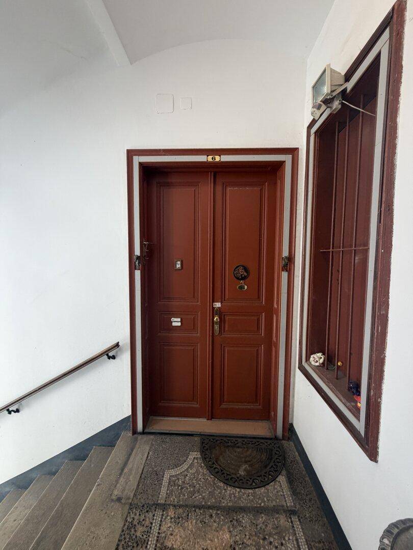 Eingangstür eines Mehrfamilienhauses mit Treppe und Fenster.
