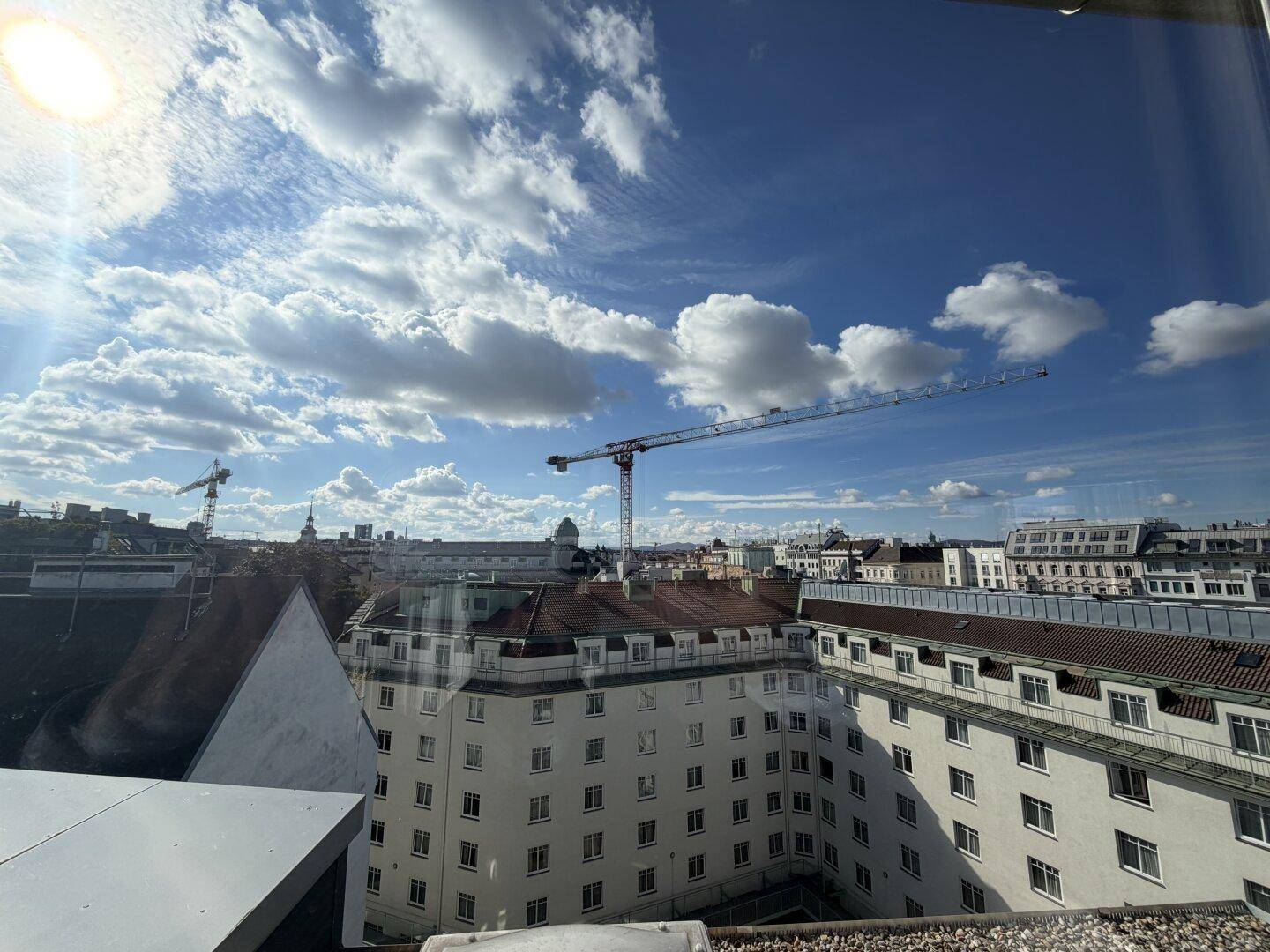 Weitläufiger Stadtblick mit Baukränen und Gebäuden unter einem strahlend blauen Himmel.