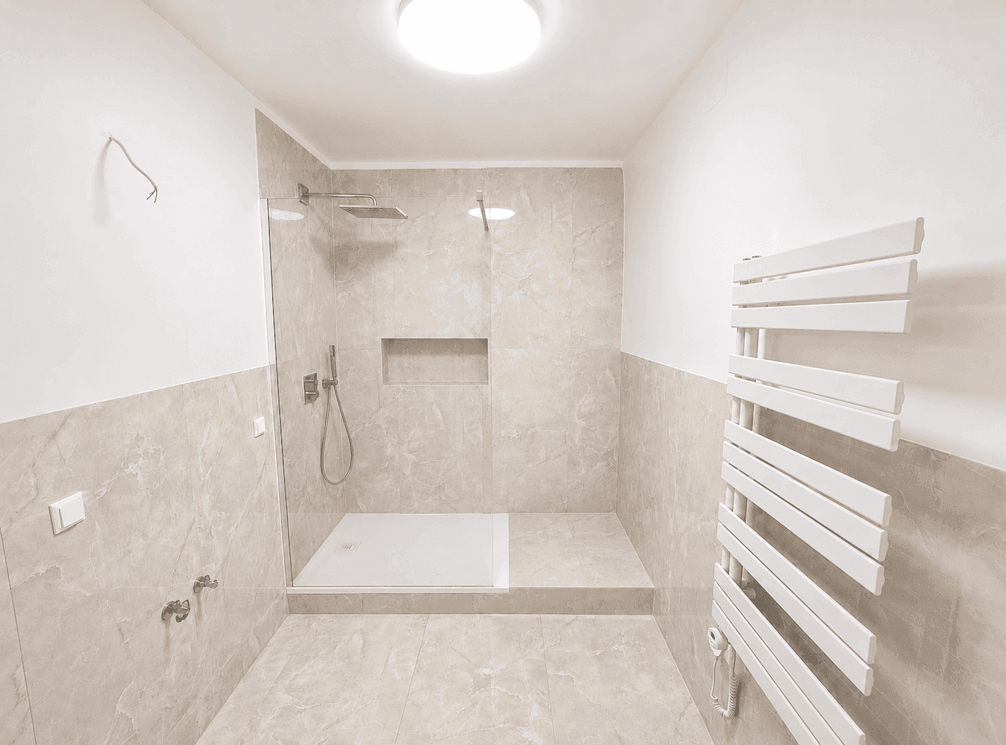 Modernes Badezimmer mit beigefarbenen Fliesen, ebenerdiger Dusche und Handtuchheizkörper.