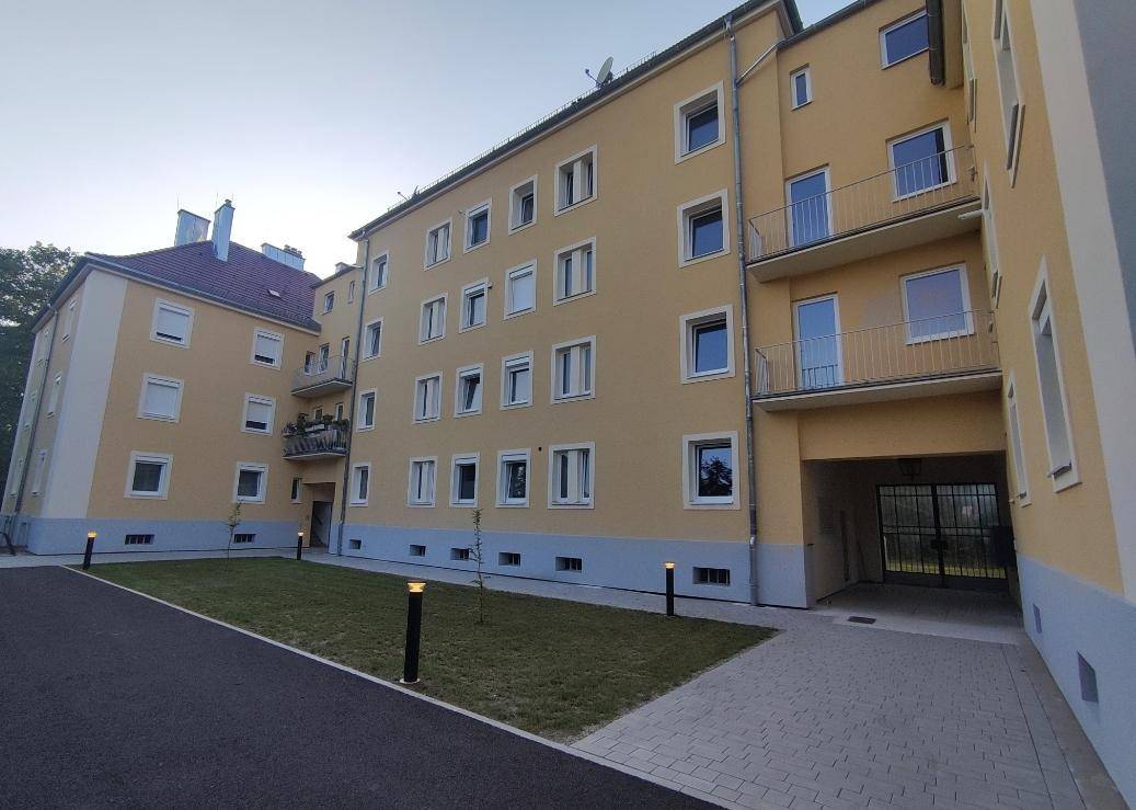 Mehrstöckiges Apartmentgebäude mit gelber Fassade, blauen Akzenten und mehreren Balkonen.