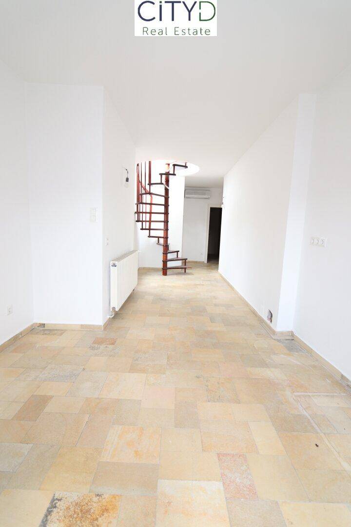 Geräumiger Flur mit Steinfliesenboden und einer eleganten Wendeltreppe, die in die oberen Etagen führt.