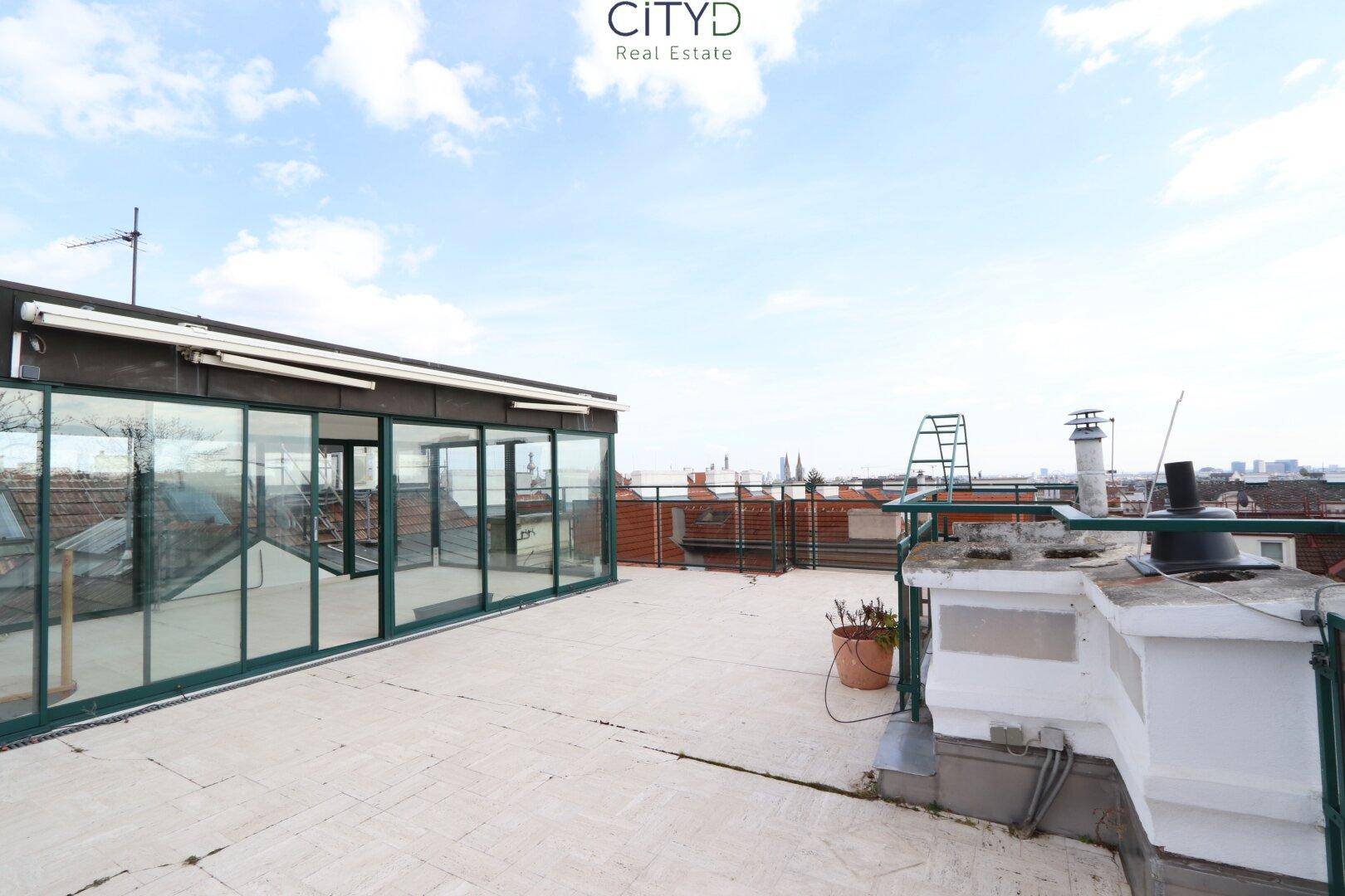 Große Dachterrasse mit weitem Blick über die Dächer der Stadt und den Himmel.