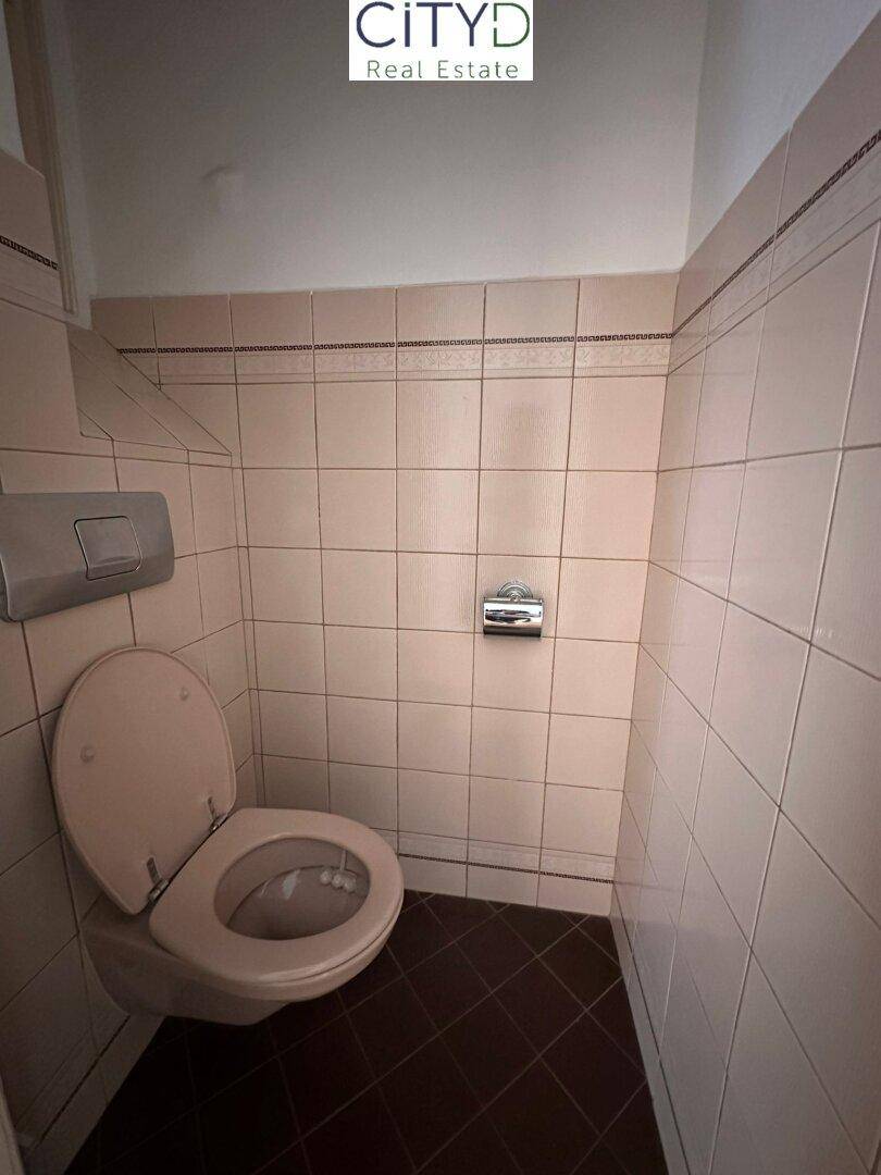 Separate Toilette mit beigefarbenen Fliesen und einem einfachen WC.