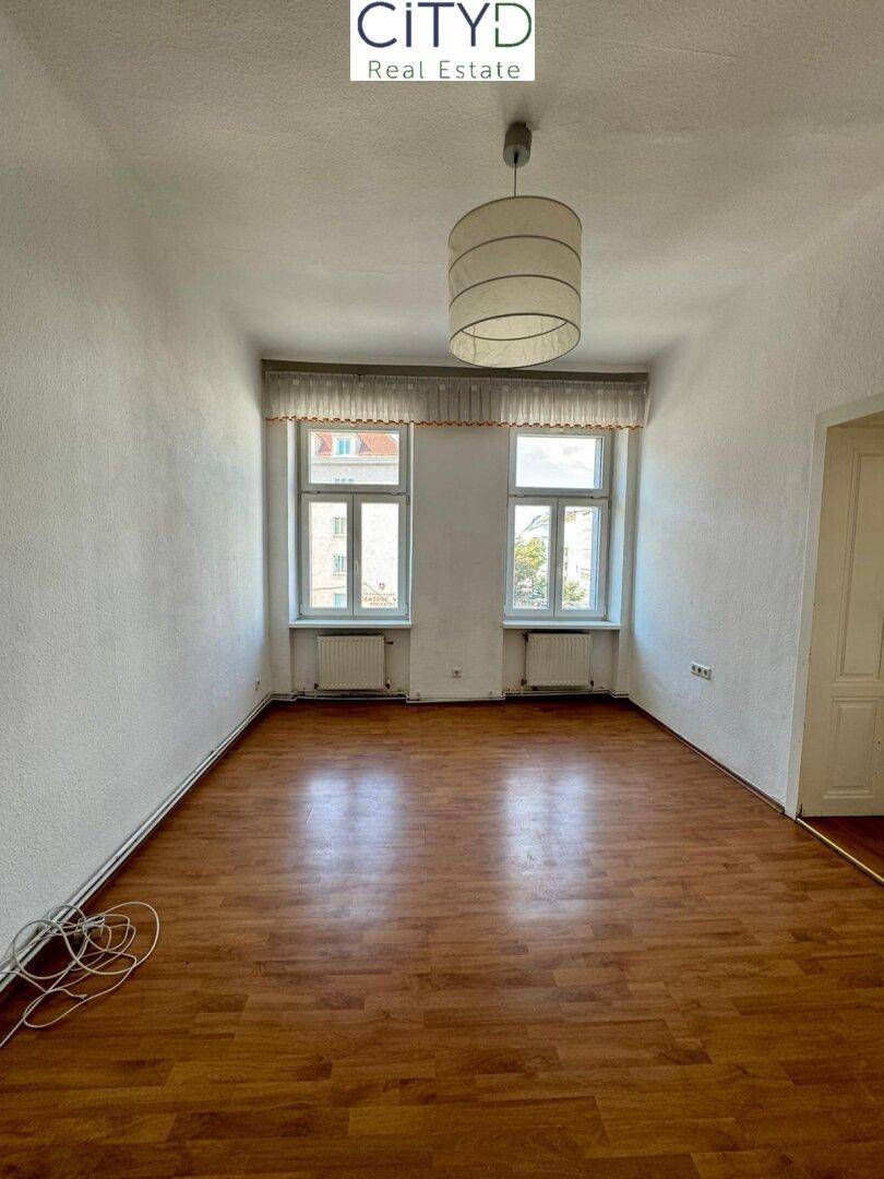 Geräumiges, helles Zimmer mit Laminatboden und zwei Fenstern, ideal für Wohn- oder Schlafbereich.