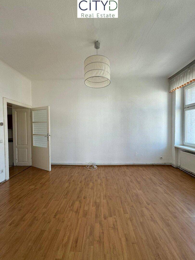 Helles Zimmer mit Laminatboden und Fenster, bietet vielseitige Nutzungsmöglichkeiten für Bewohner.