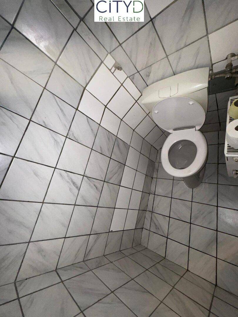 Kleines WC mit weißen Fliesen und einfacher Toilette.