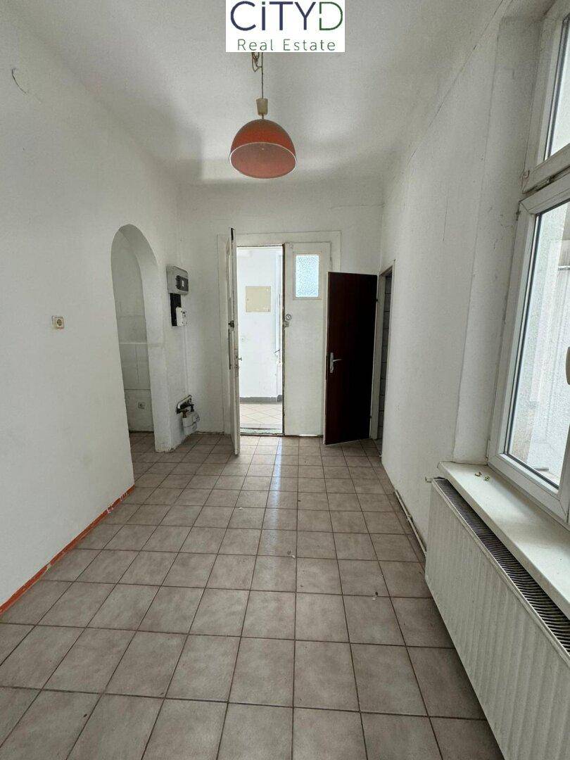 Flur mit Fliesenboden, Fenster und Zugang zu weiteren Räumen.