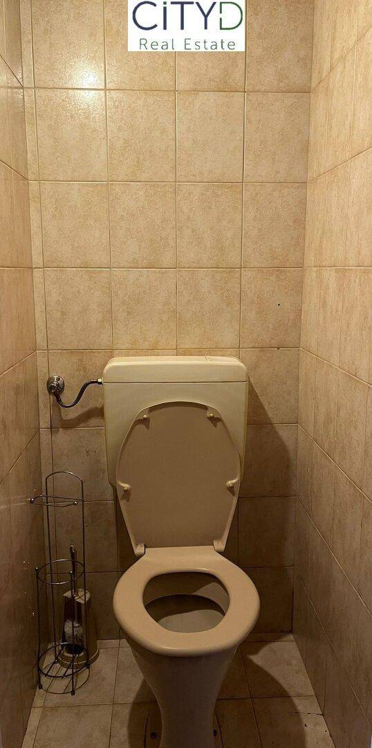 Separate Toilette mit beigen Fliesen und Standard-WC, in einfachem Zustand.