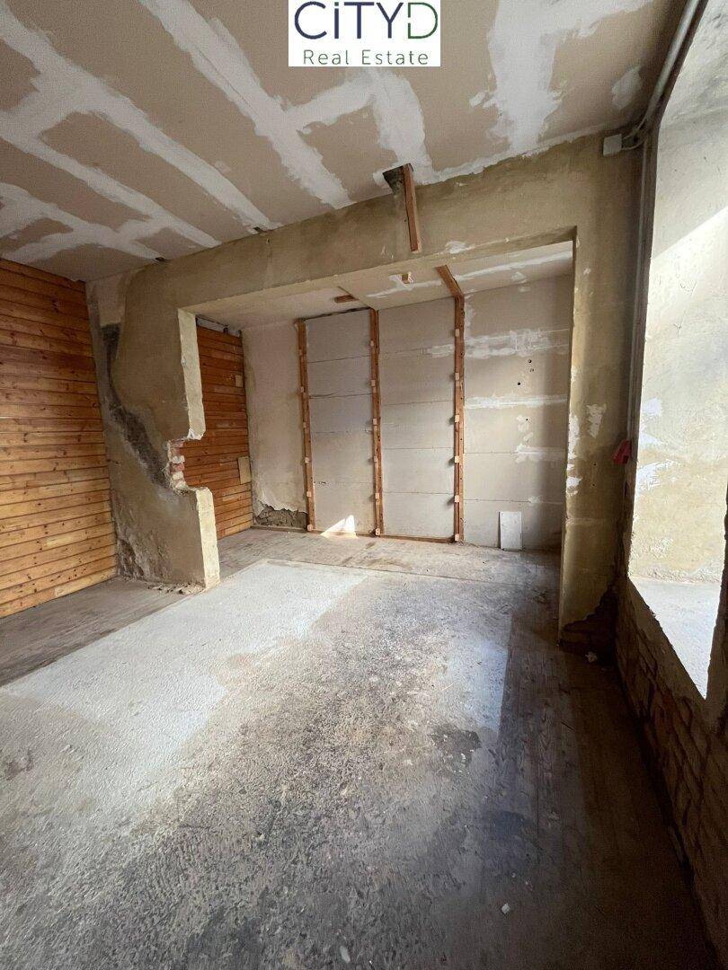 Unfertiger Innenraum mit Betonboden und teilweise verkleideten Wänden, bereit zur Renovierung.