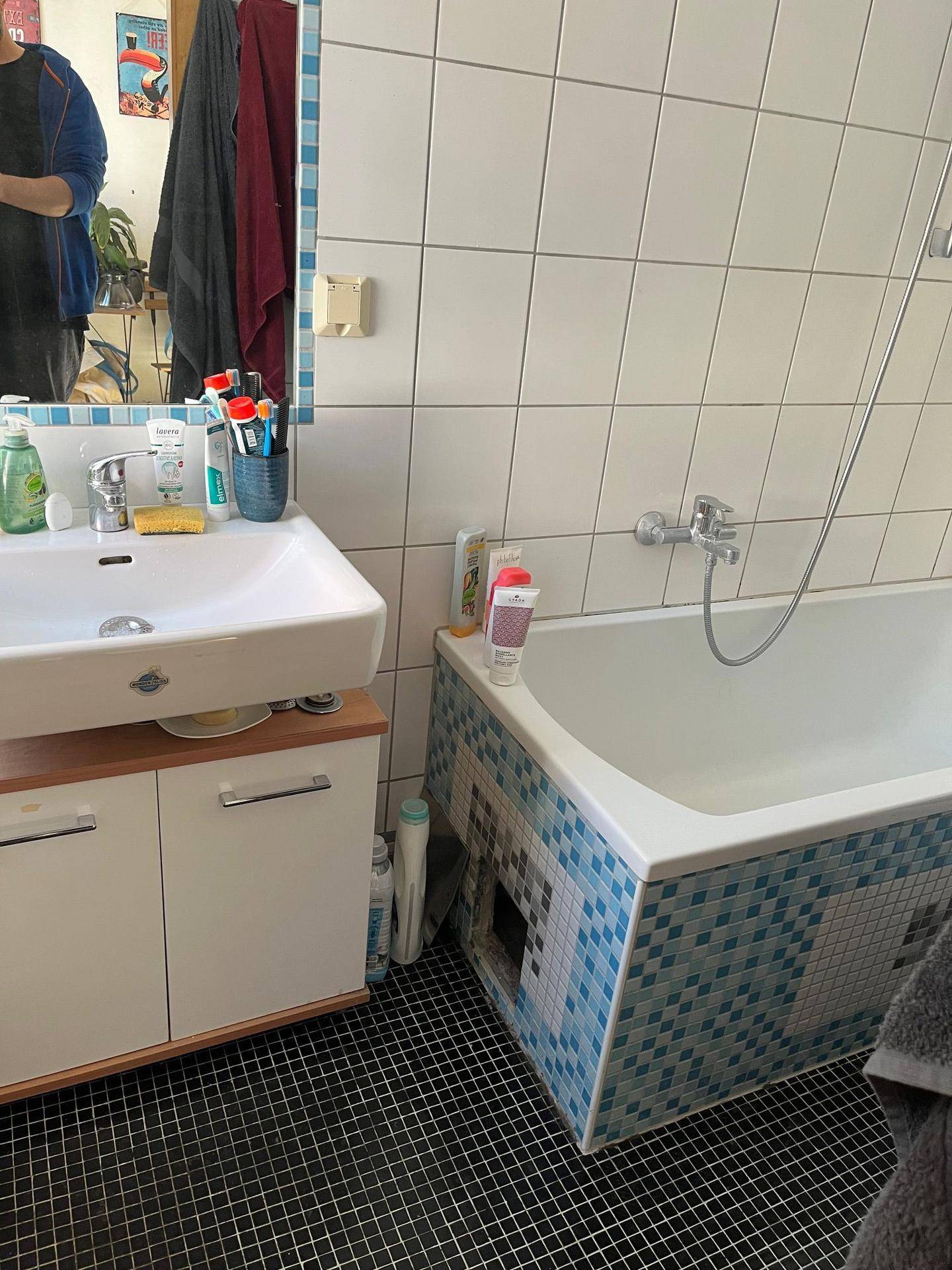 Badezimmer mit Waschbecken, Badewanne und Fliesen in Weiß und Blau.