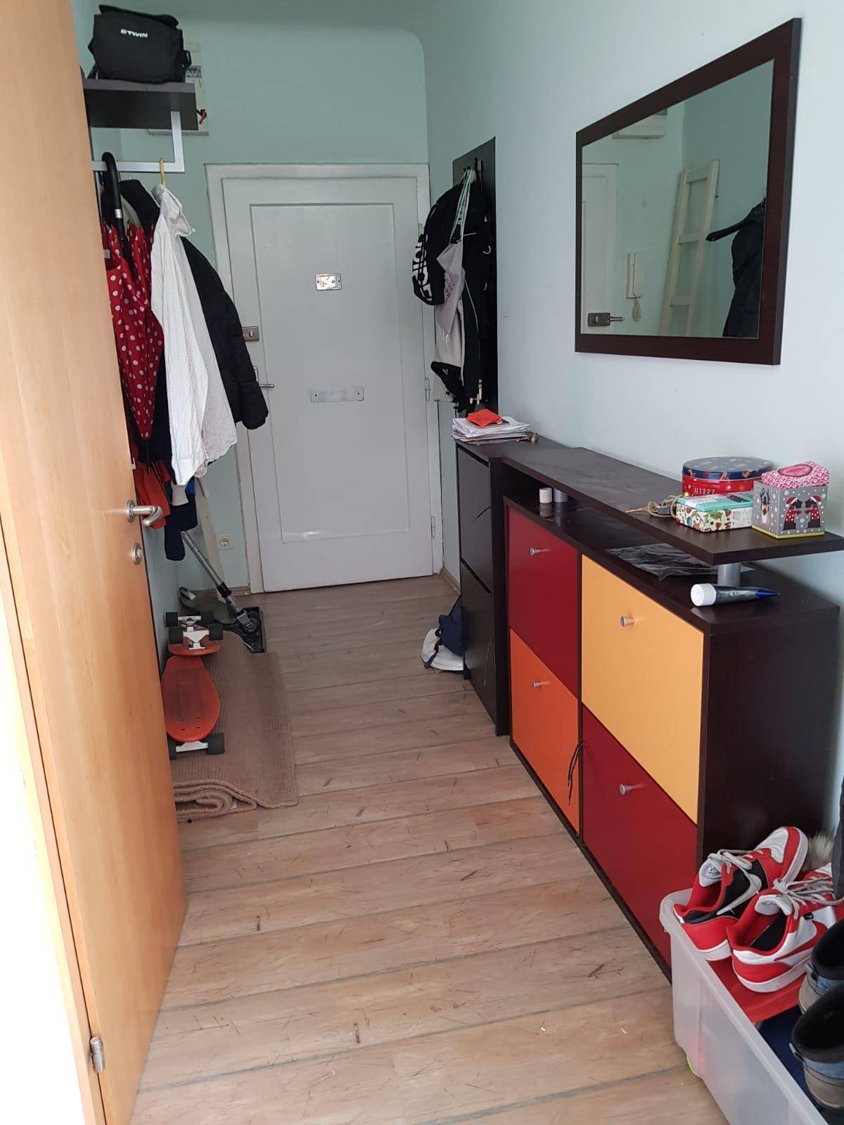 Flur mit farbenfrohem Schuhschrank und Spiegel, der den Eingangsbereich aufhellt.