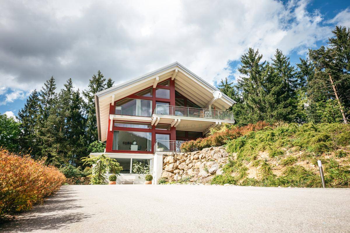 Modernes Holzhaus mit großen Glasfronten und Satteldach in alpiner Umgebung.
