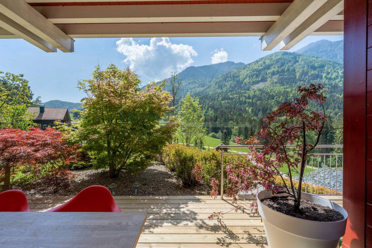 Überdachte Terrasse mit Pflanzen und Panoramablick auf die umliegende Berglandschaft.