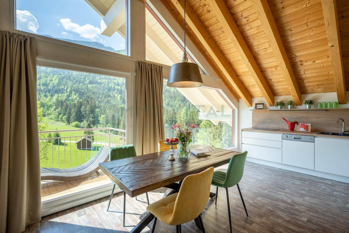 Helle Küche mit Essbereich im Dachgeschoss, Holzbalken und Bergblick.