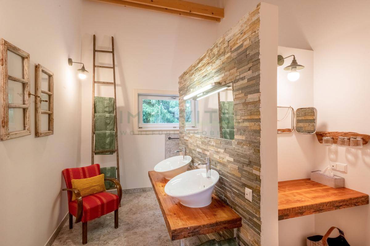 Modernes Badezimmer mit Doppelwaschbecken, Steinwand und Fenster.
