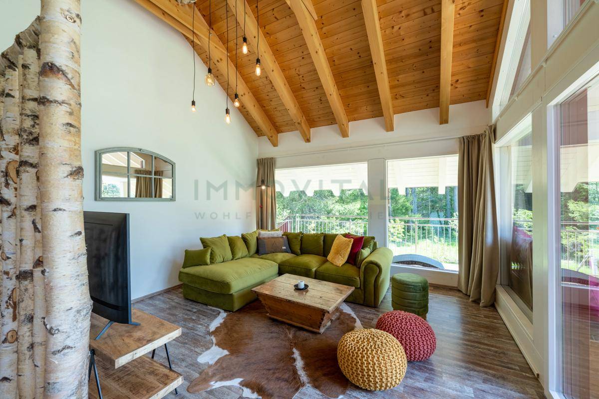 Geräumiges Wohnzimmer mit Holzbalkendecke, großen Fenstern und gemütlicher Sitzecke.