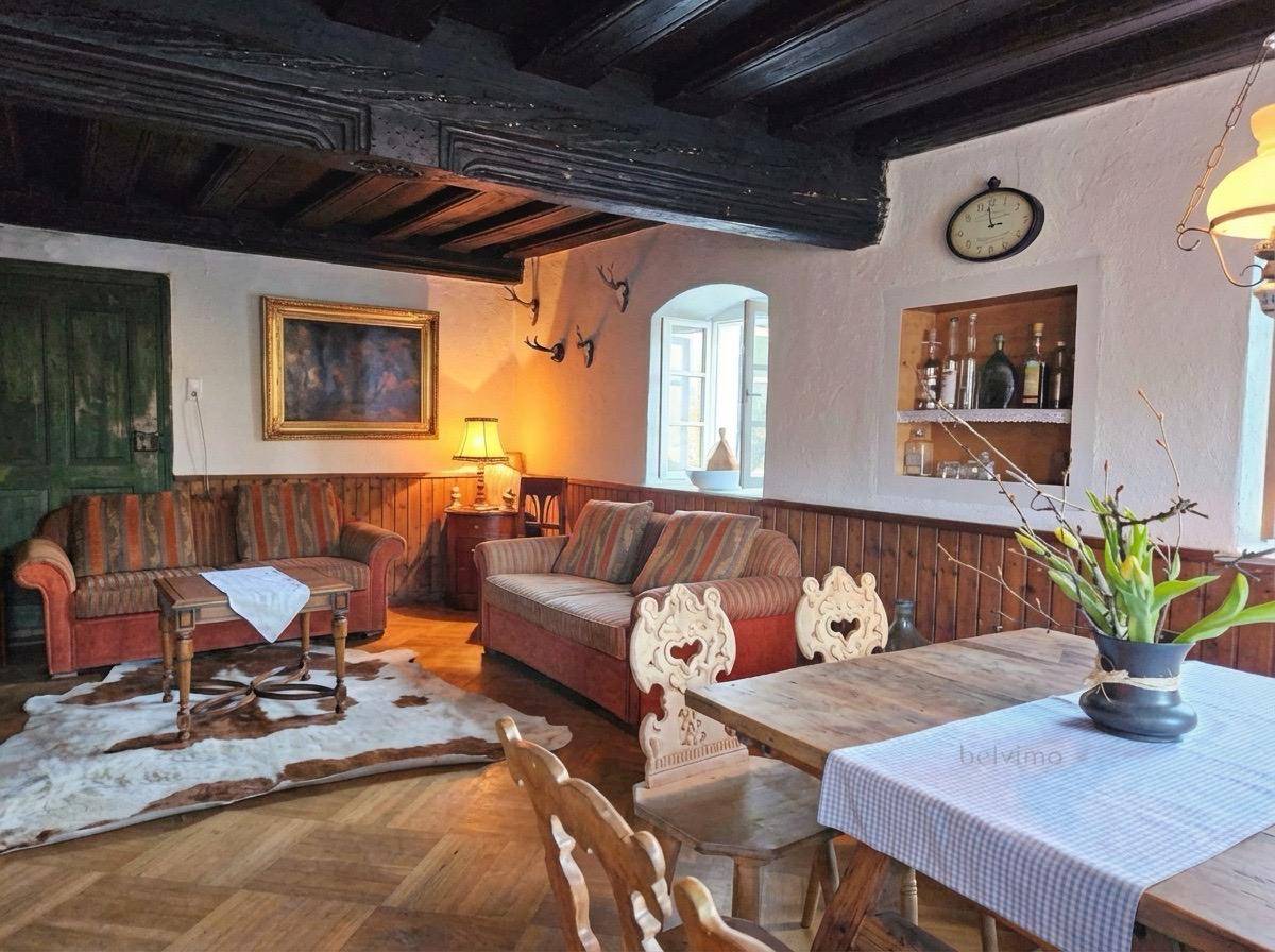 Gemütlicher Wohn- und Essbereich im traditionellen Stil mit dunklen Holzbalken, rustikalen Möbeln und einem Kuhfellteppich.