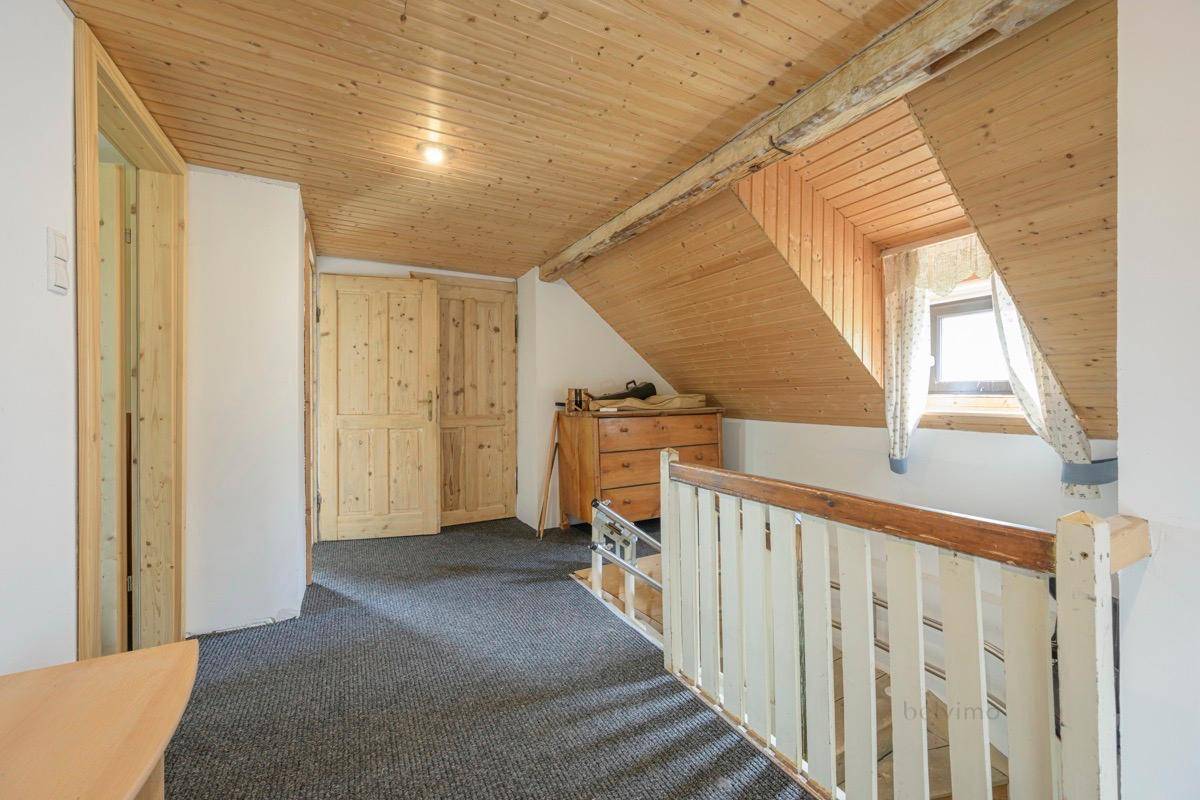 Dachgeschoss-Flur mit Holzverkleidung, Teppichboden und Dachschräge.