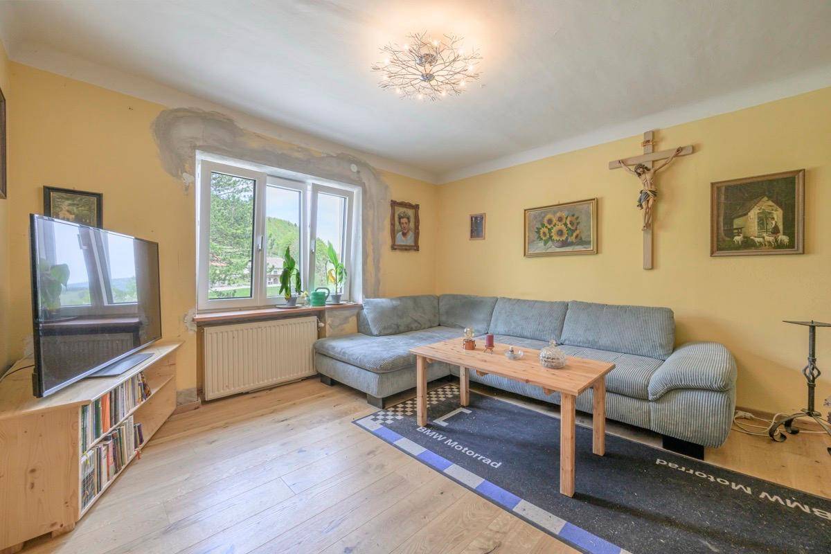 Helles Wohnzimmer mit Holzboden, bequemer Couch und Blick ins Grüne.