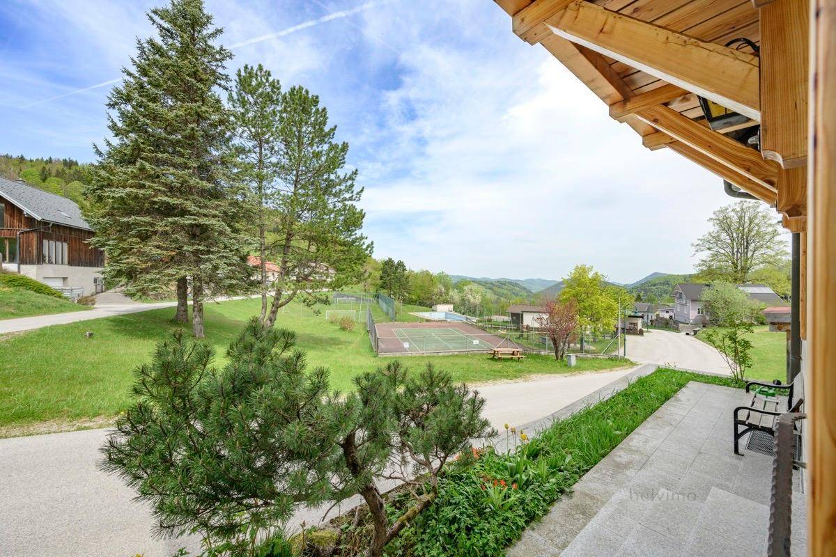 Weitläufiger Blick von der Terrasse auf die umliegende Landschaft und einen Tennisplatz.