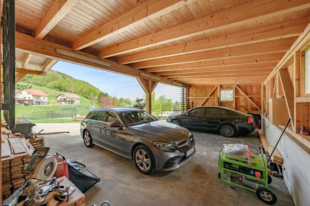 Geräumiger Holzcarport mit Platz für zwei Fahrzeuge und Blick auf die Umgebung.