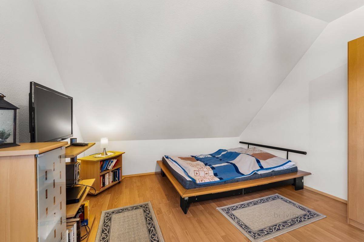 Gemütliches Schlafzimmer im Dachgeschoss mit Holzboden und schräger Decke.