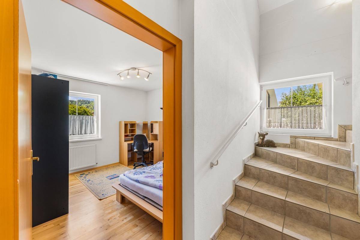 Treppenaufgang mit Fliesenstufen und Zugang zu einem weiteren Zimmer mit Blick ins Grüne.
