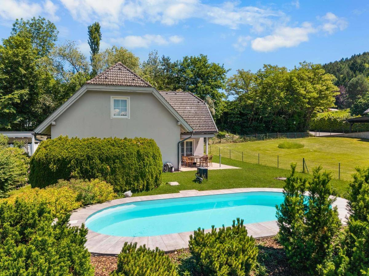 Außenansicht des Hauses mit Pool, Garten und umgebender grüner Landschaft.