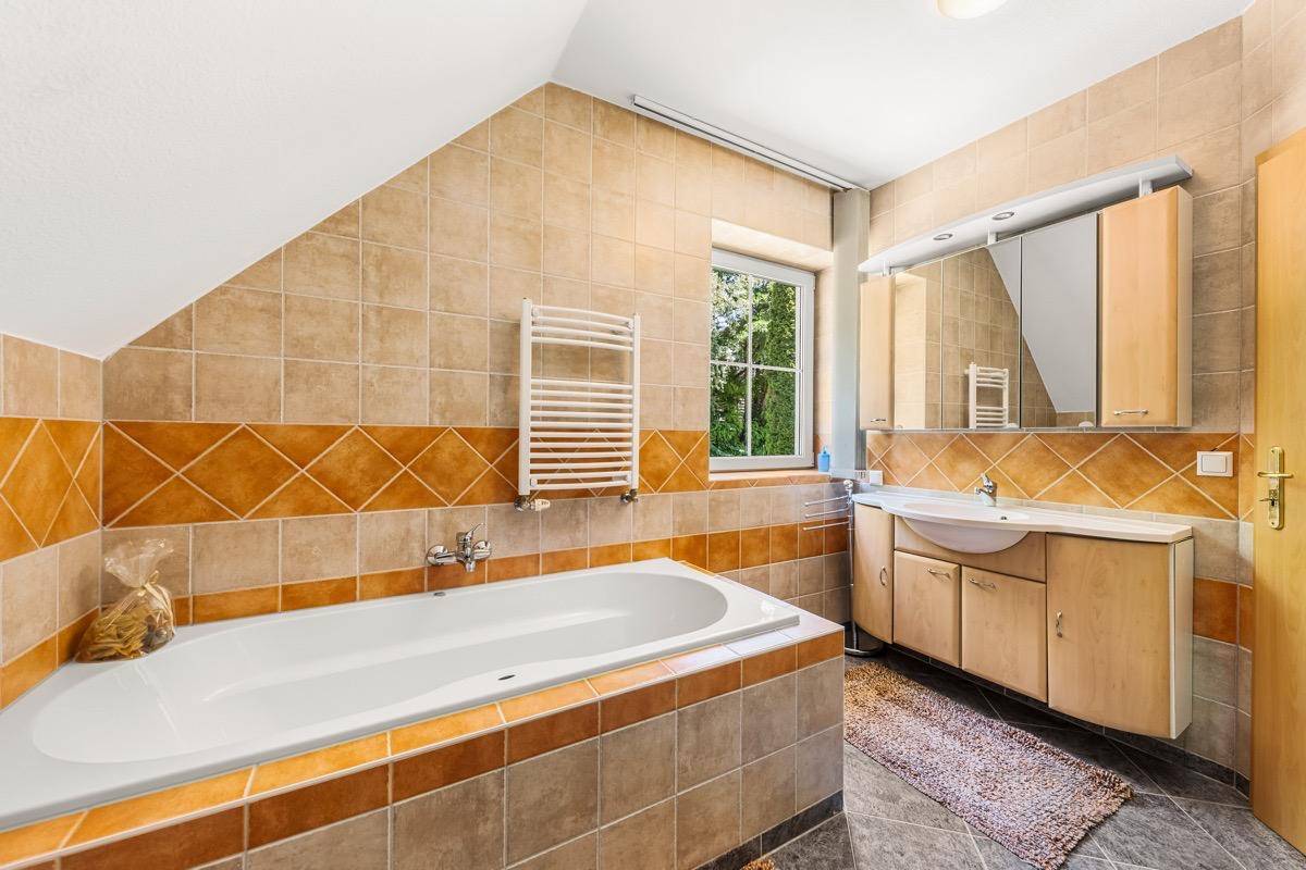 Badezimmer im Dachgeschoss mit Badewanne, Fliesen und beheiztem Handtuchhalter.