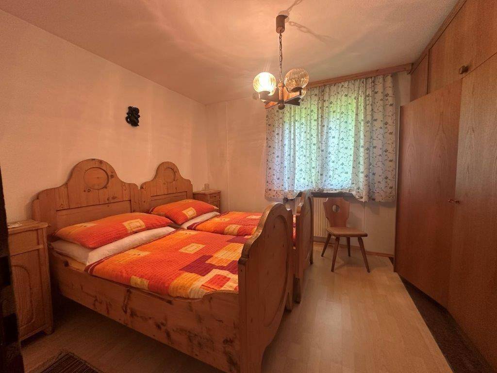 Gemütliches Schlafzimmer im traditionellen Stil mit zwei Einzelbetten aus hellem Holz und floralen Vorhängen.