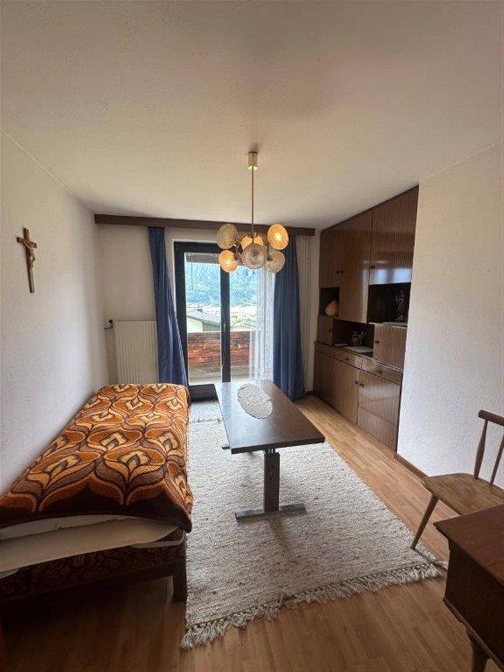 Helles Zimmer mit Einzelbett, Holzboden und Zugang zu einem Balkon mit schöner Aussicht.
