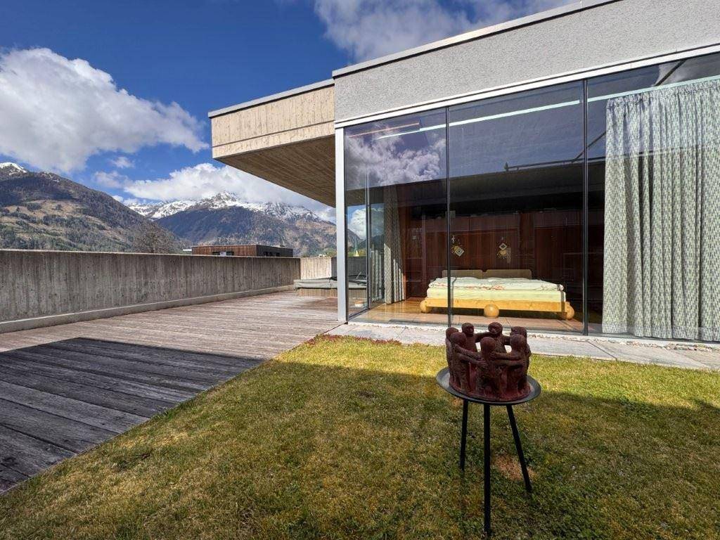 Geräumige Holzterrasse mit Rasenfläche und Blick auf ein Schlafzimmer und die umliegenden Berge.