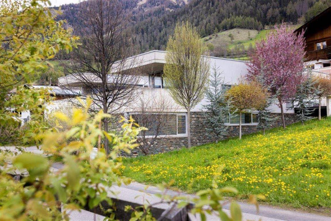 Modernes Gebäude in ländlicher Umgebung mit blühenden Bäumen und Wiesen im Frühling.