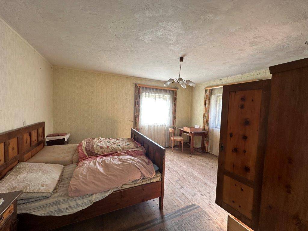Geräumiges Schlafzimmer mit Holzbett, Holzboden und Fenster, das viel Tageslicht hereinlässt.