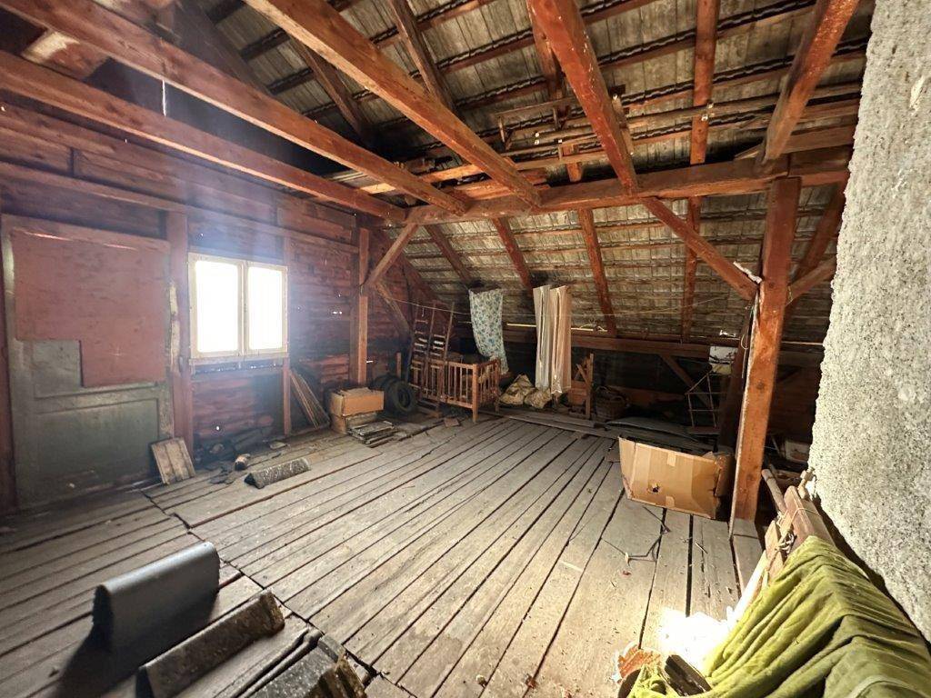 Dachboden mit sichtbaren Holzbalken und Holzboden, bietet viel Potenzial für Ausbau.